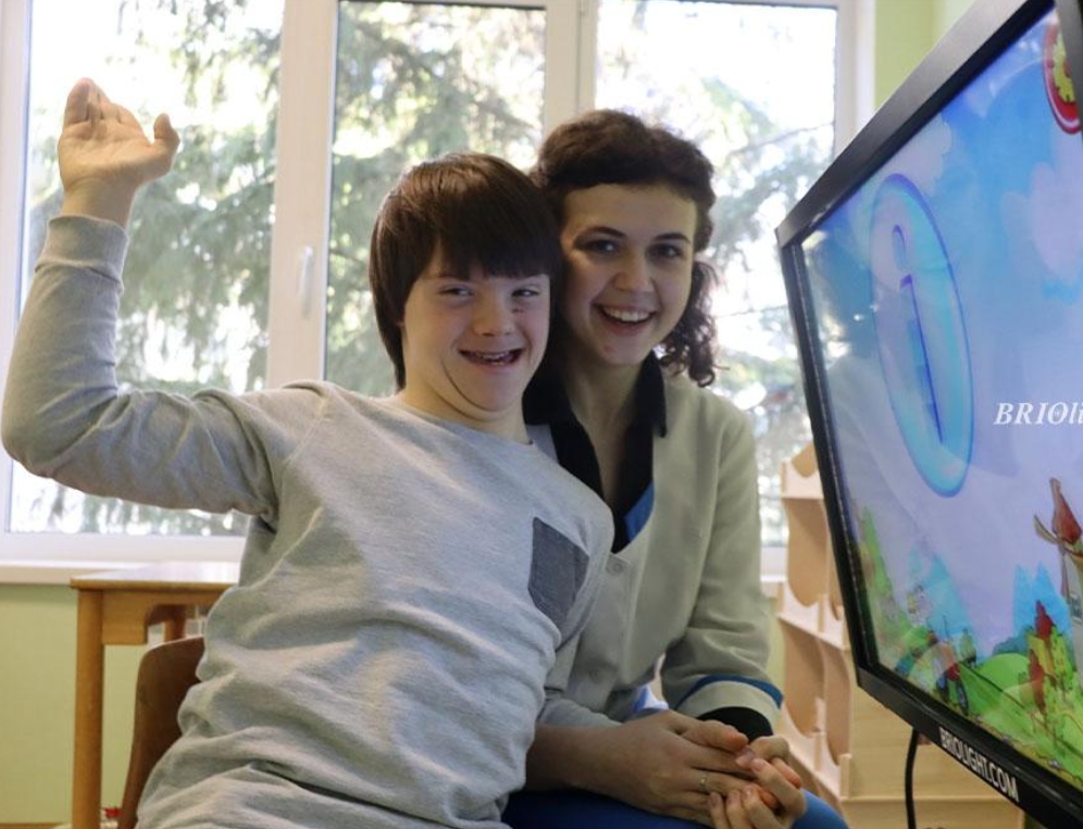 A child and specialist work with a Briolight interactive display